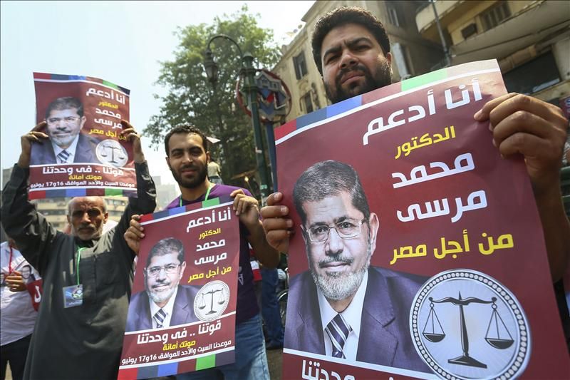 Simpatizantes del candidato de los Hermanos Musulmanes, Mohamed Mursi, sujetan un cartel electoral en la plaza Tahrir, tras saber el resultado de las elecciones presidenciales en El Cairo, Egipto, hoy lunes, 18 de junio de 2012.