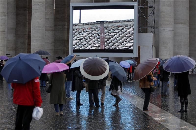 Varias personas observan una pantalla gigante instalada en la plaza de San Pedro, en Ciudad del Vaticano, el 12 de marzo del 2013.