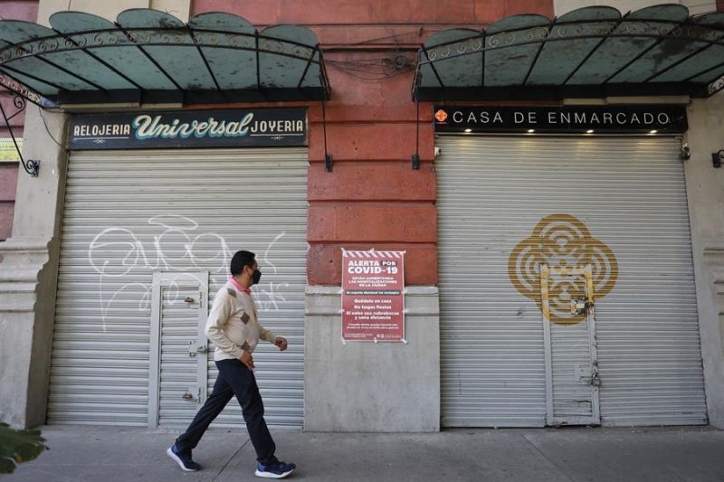 Un hombre camina frente a dos locales cerrados debido a la pandemia, en Ciudad de México.