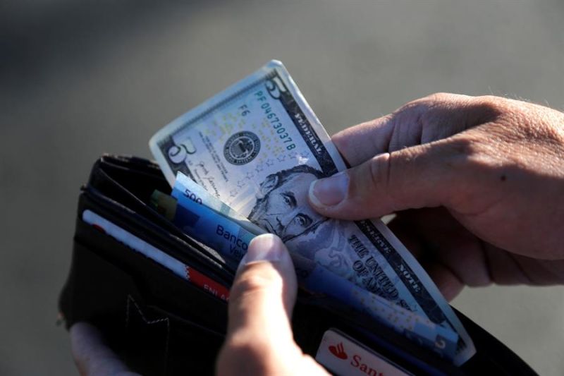 Fotografía de archivo de una persona que guarda en su cartera un billete de cinco dólares, el 28 de enero de 2022 en Tepatitlán, estado de Jalisco (México).