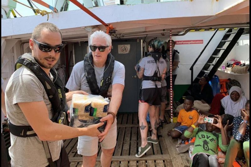 Fotografía de la ONG española Open Arms de Richard Gere (c), que ha entregado víveres este viernes en el barco de la organización que acoge a 121 inmigrantes que esperan, a la altura isla italiana Lampedusa, para pisar tierra firme desde hace una semana.