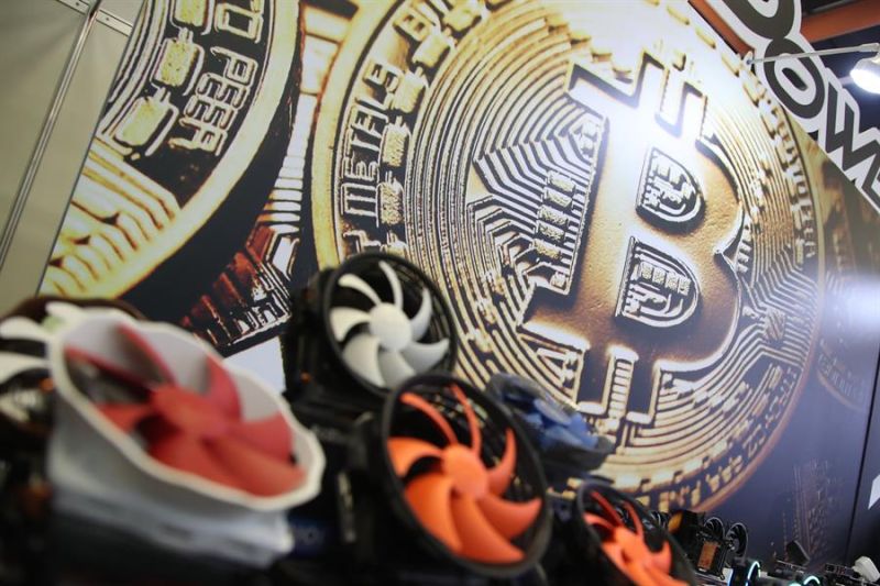 Se ve un logotipo de bitcoin junto a los fanáticos de las computadoras.