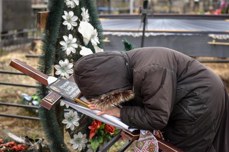 Alla, madre de una persona asesinada por soldados rusos en Bucha en marzo de 2022, llora mientras sostiene una cruz con su retrato, en el cementerio municipal de esta ciudad del área de Kiev, el 18 de abril de 2022. EFE/EPA/OLEG PETRASYUK
