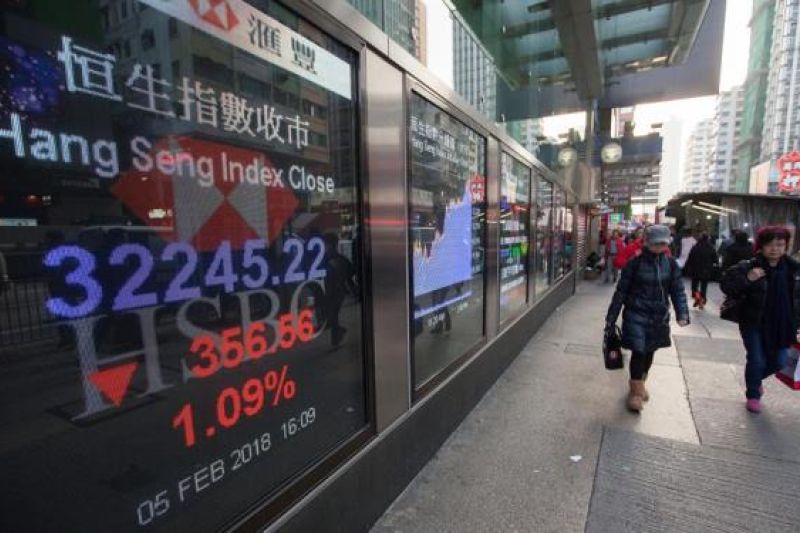 Peatones pasan por delante de una pantalla con el valor de cierre del índice Hang Seng, en Hong Kong, China.