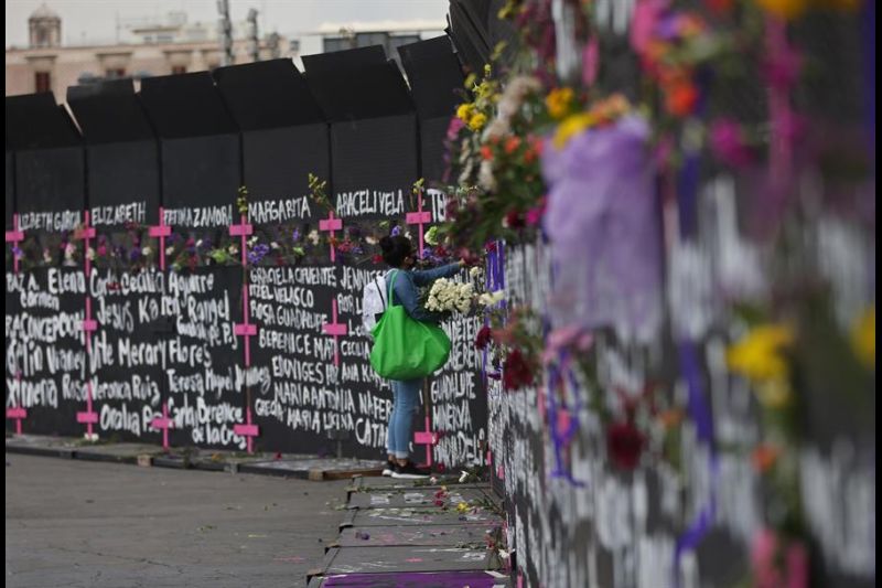 Una mujer coloca flores y carteles con nombres de víctimas por feminicidios en cercos metálicos instalados por el gobierno capitalino en una protesta contra los feminicidios este 7 de marzo de 2021, en Ciudad de México (México). 