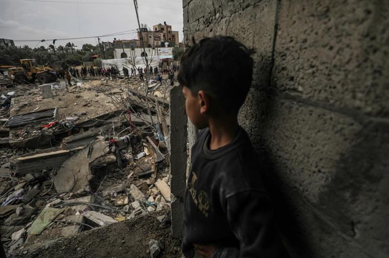 Un niño observa cómo los palestinos buscan a personas desaparecidas bajo los escombros de una casa destruida en el campo de refugiados de Al Nusairat, al sur de Gaza Franja, 19 de marzo de 2024. EFE/EPA/MOHAMMED SABLE 01 040124