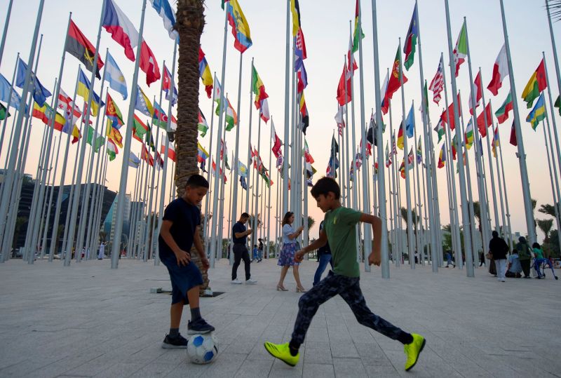 Niños juegan al fútbol en una plaza de Doha, capital de Catar, rodeado de las banderas de las selecciones participantes en el próximo Mundial de fútbol. 01 201122