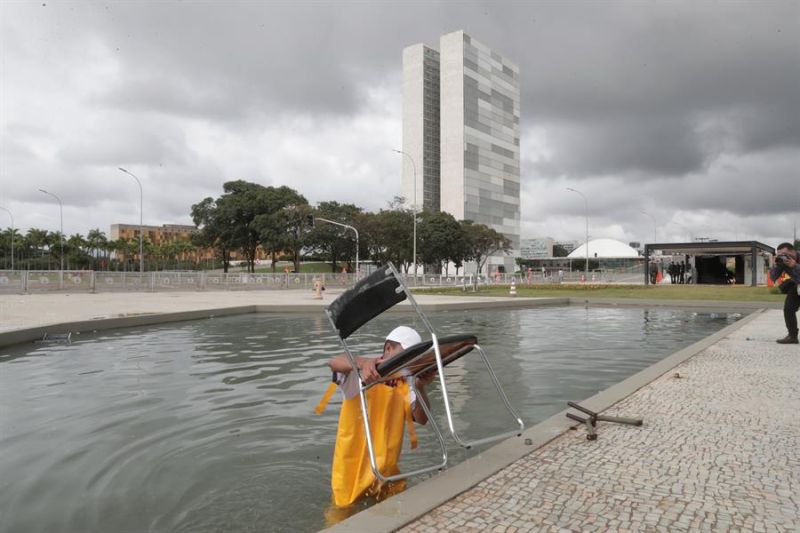 Un hombre saca hoy una silla de uno de los cuerpos de agua que rodean el Palacio de Planalto, en Brasilia, después de que manifestantes bolsonaristas tomaran en la víspera la Plaza de los Tres Poderes para invadir los edificios gubernamentales. 01 090123